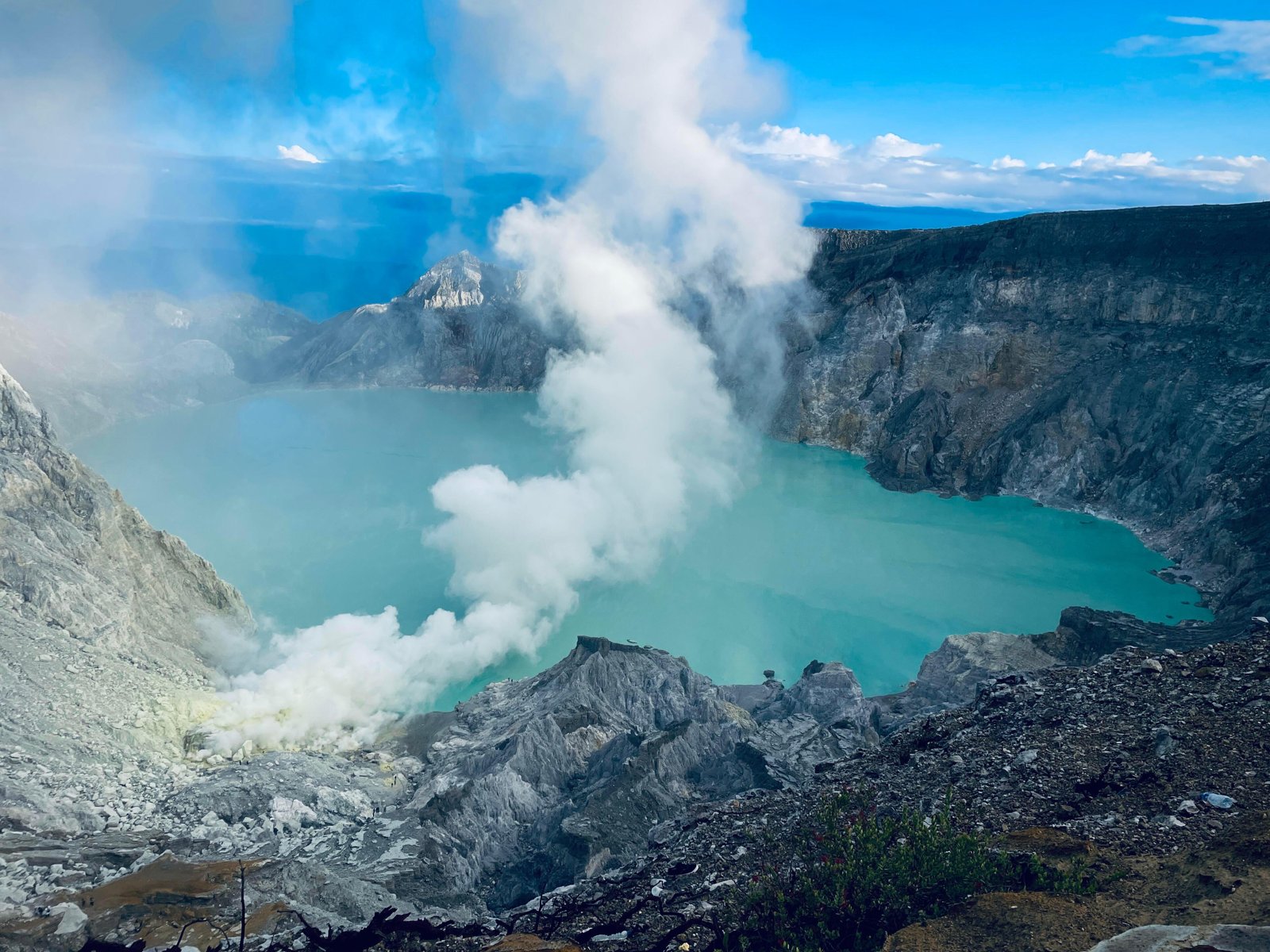 Turquoise crater lake of Ijen volcano with sulfur smoke